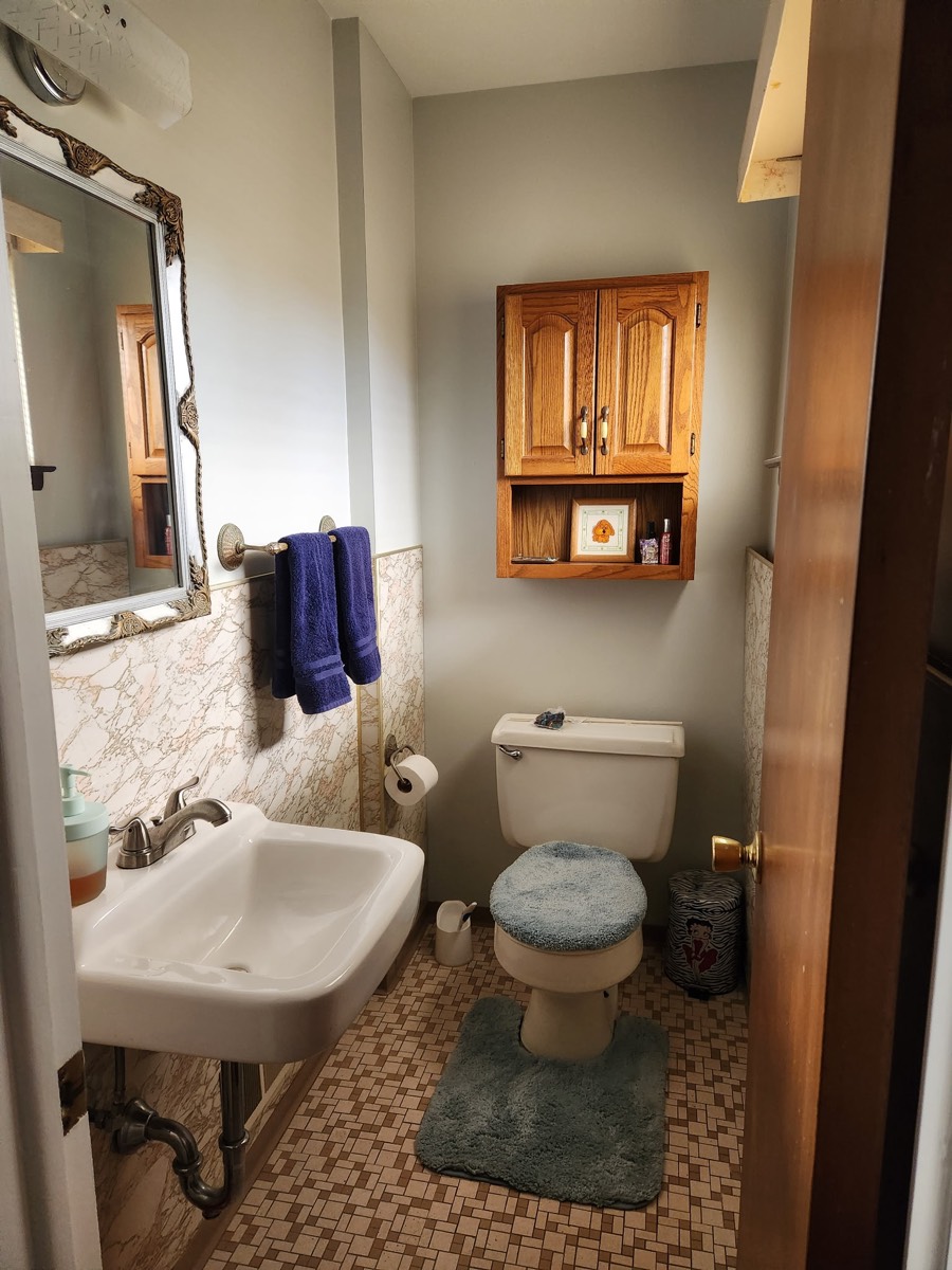 Half Bath Update — before, with marble-look wallpaper and an oak medicine cabinet